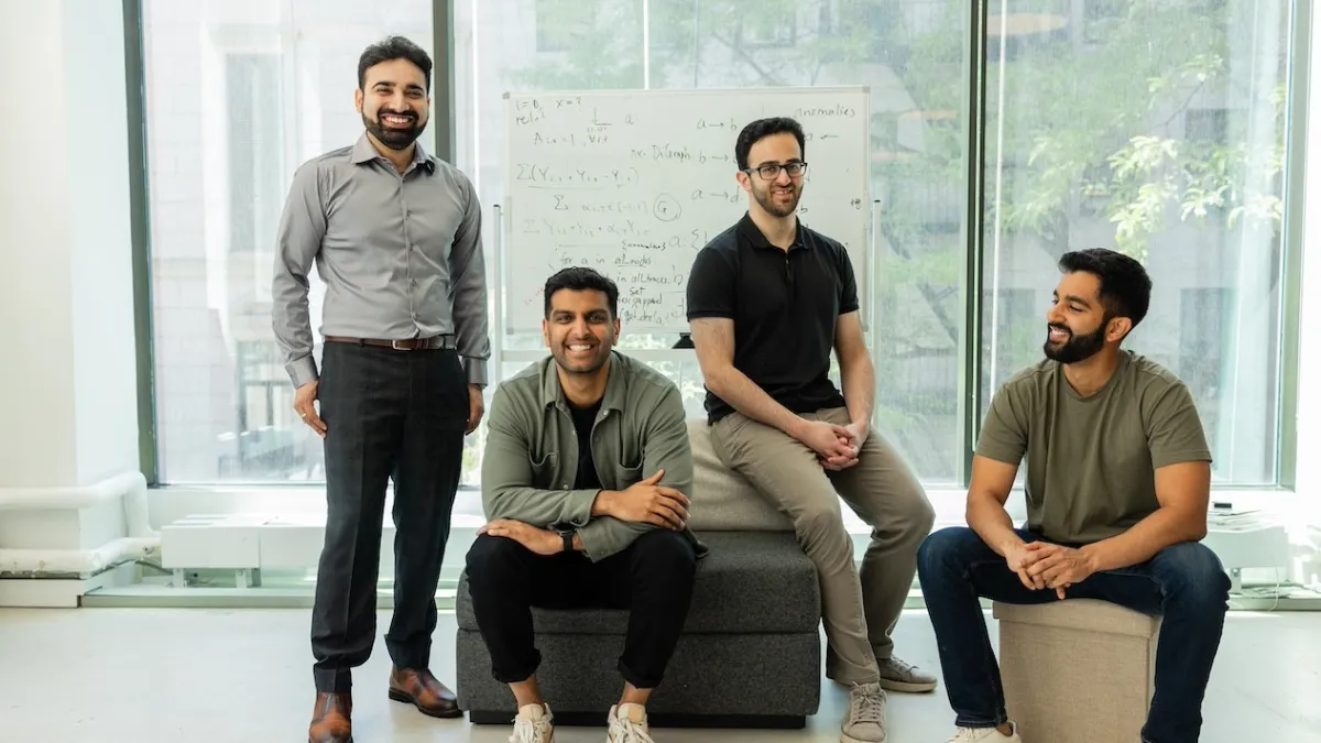 Smiling co-founders of AI observability startup Traversal, with handwritten formulas in the background, where theory meets tech.