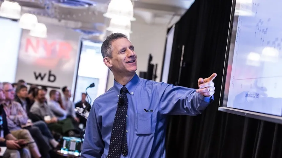Andrew Gelman pointing at screen in front of crowd