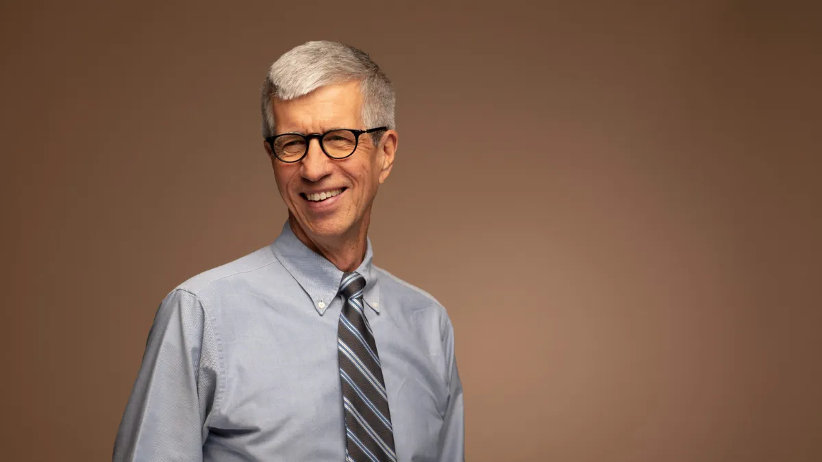 Headshot of Professor Kent Daniel with brown background