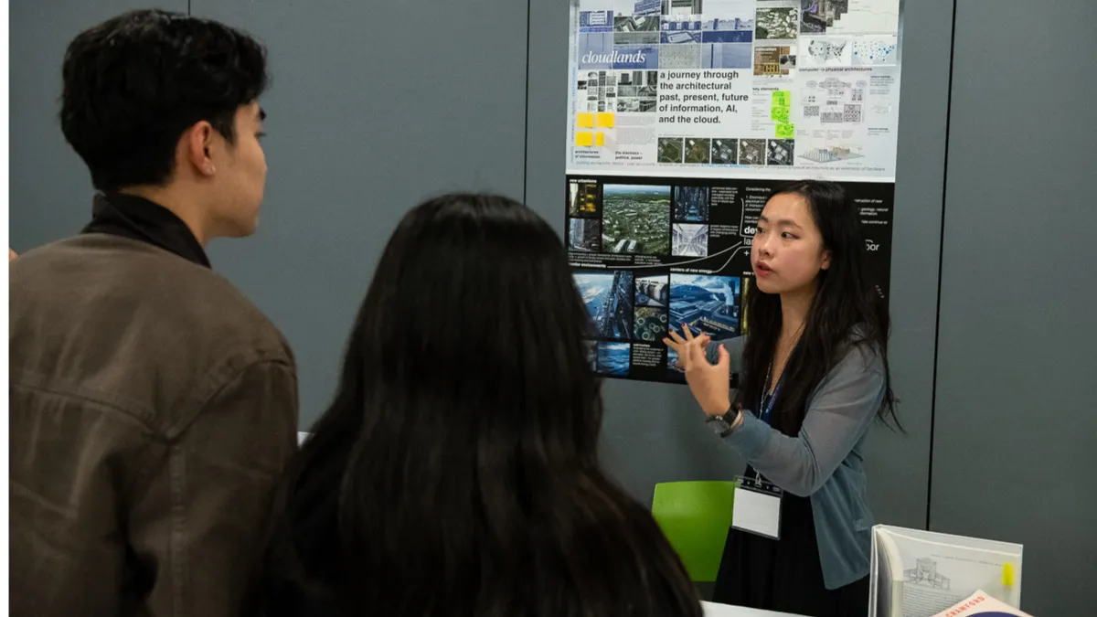 photograph of students standing over a table presenting their research poster
