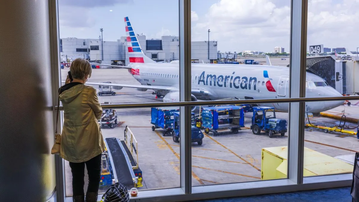 A woman looks through a window at an American Airlines plane at Miami International Airport.