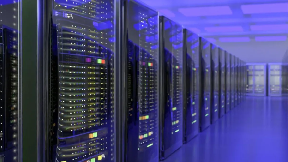 A row of high-performance computing servers in a data center, illuminated by blue lighting, reflecting off the glass panels of the server racks.
