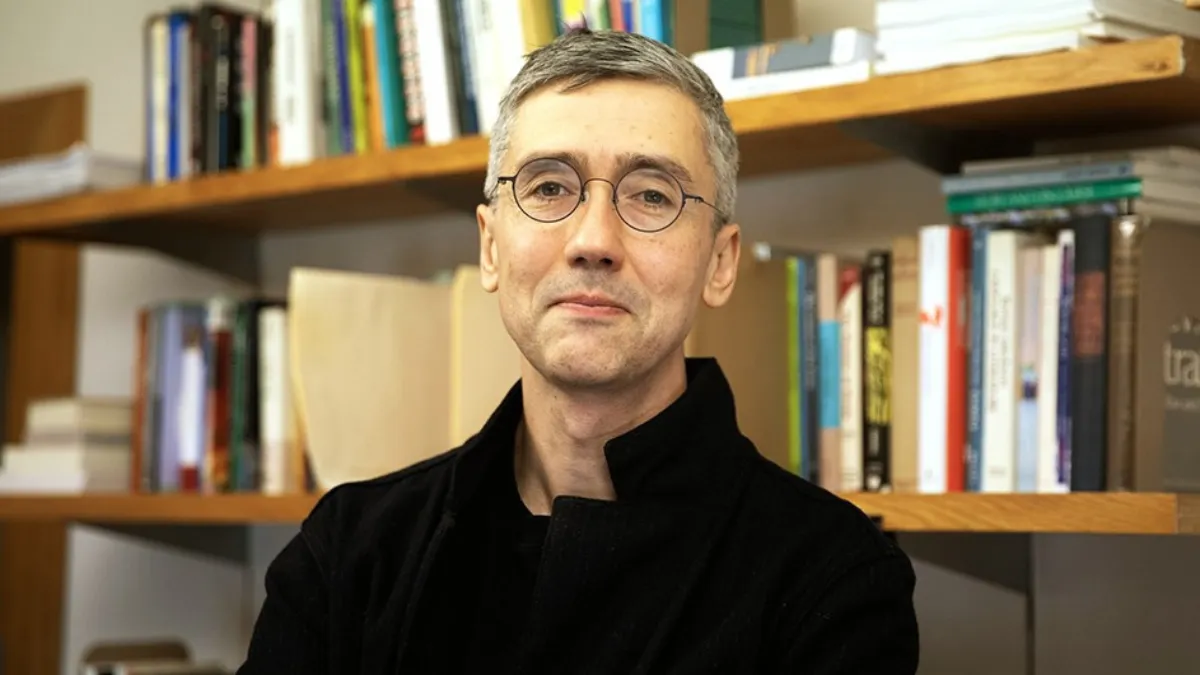 Dennis Tenen standing in front of bookshelf