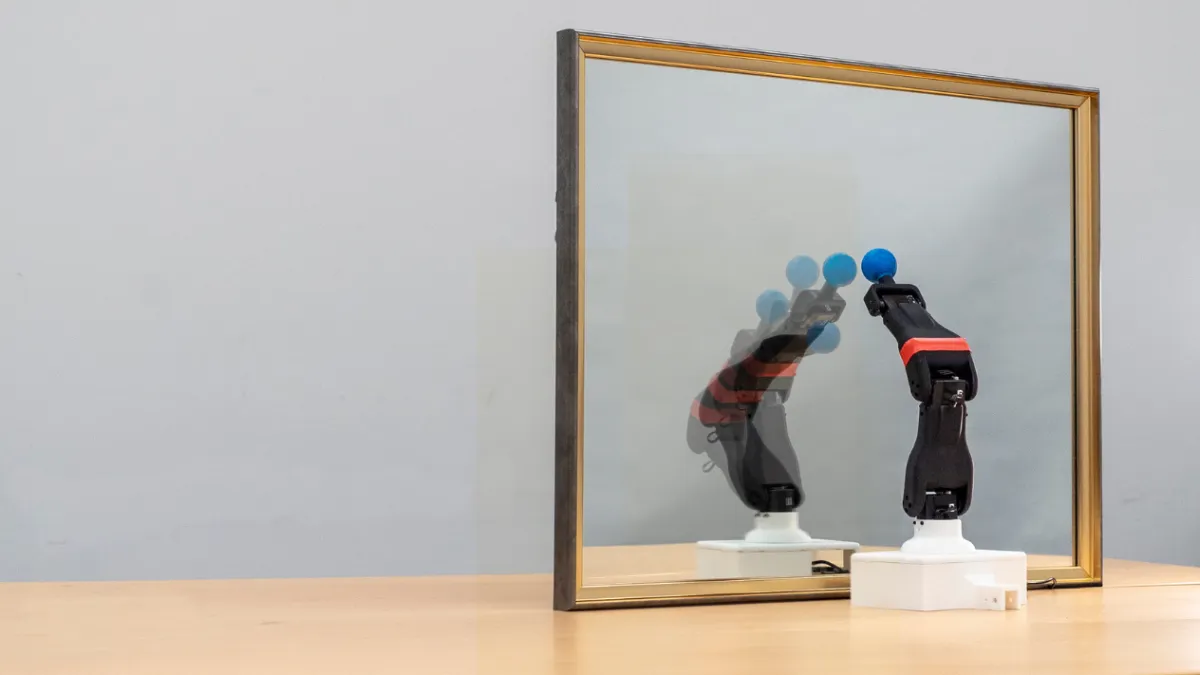 This image appears to depict a robotic arm interacting with a mirror, possibly illustrating machine learning or self-learning AI concepts.