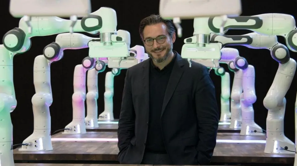 Sami Haddadin stands in front of a robot he created