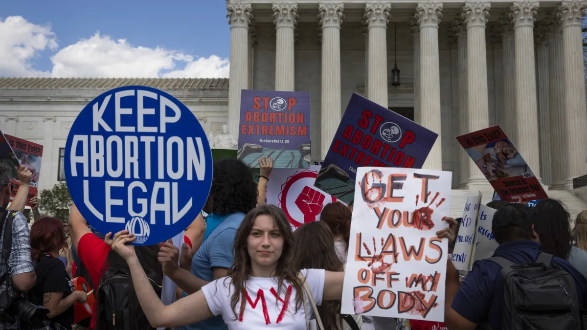 A crowd of abortion rights protesters holding signs advocating for reproductive rights and opposing abortion restrictions. Photo by Aashish Kiphayet