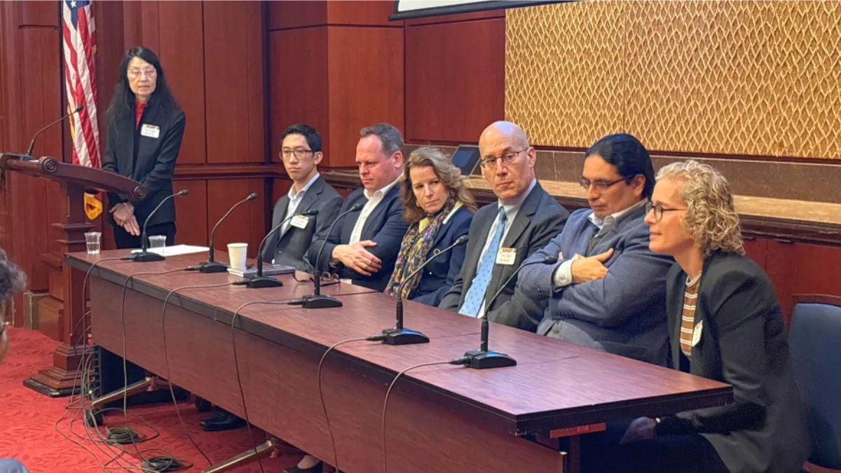 image of speakers sitting at the front of the room