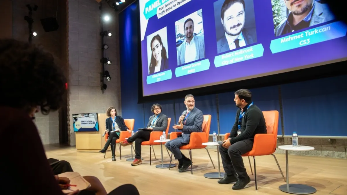 speakers onstage with presentation in the background