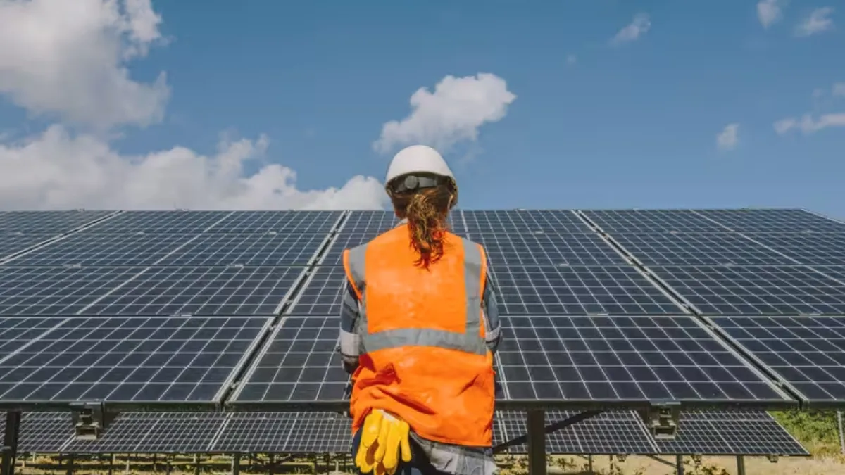 A construction worker overlooking solar panels. 