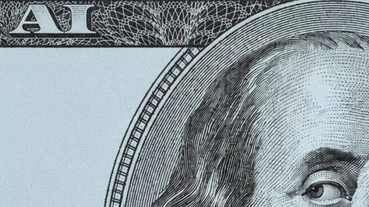 A close-up of a U.S. dollar bill with the words "AI" visible on the top left corner. 