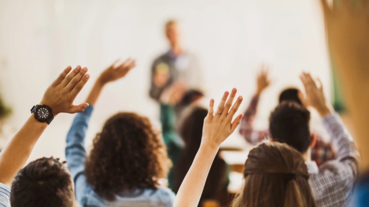 students in classroom raising hands
