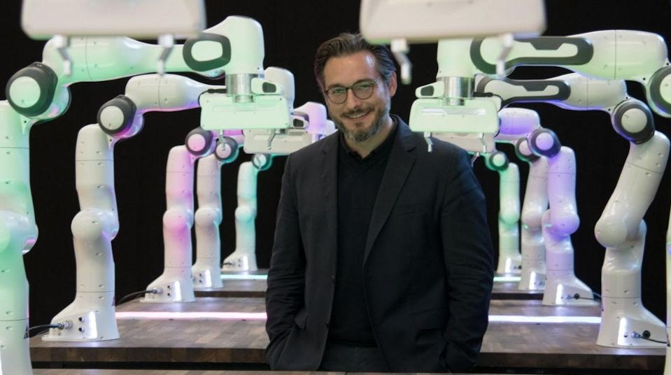 Sami Haddadin stands in front of a robot he created