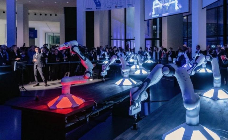 Sami Haddadin onstage with a collective AI system he created in front of a crowd